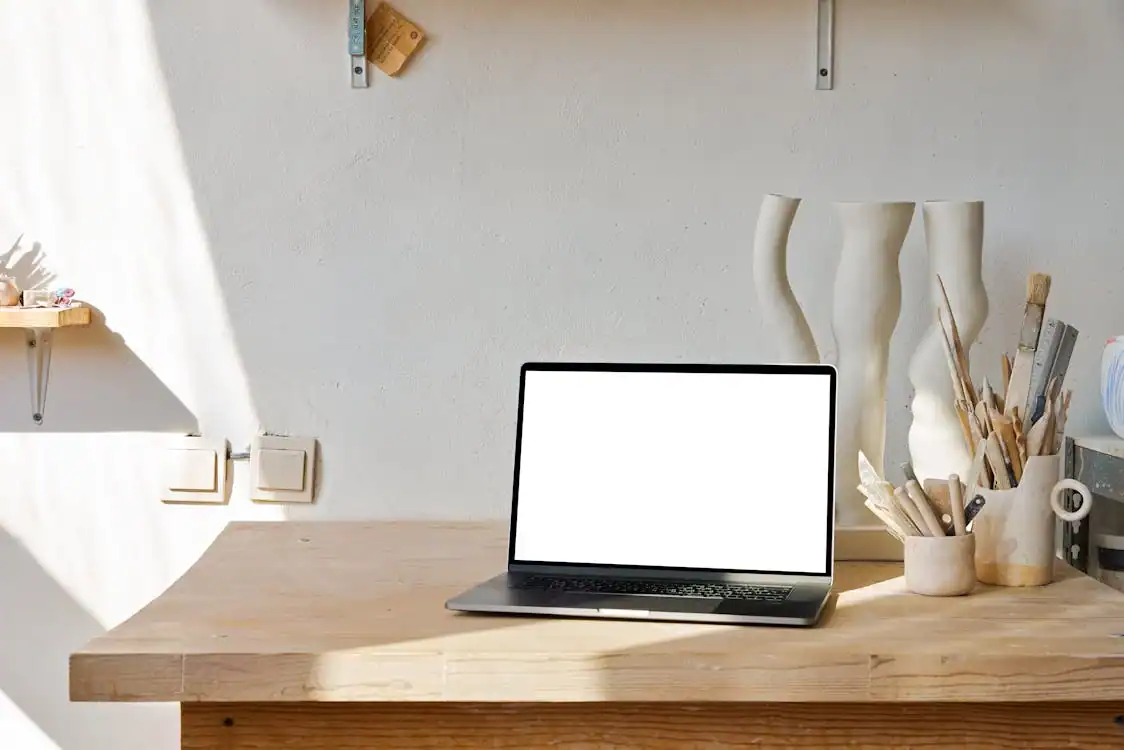 Clean workspace with open laptop and artistic tools for creative projects.